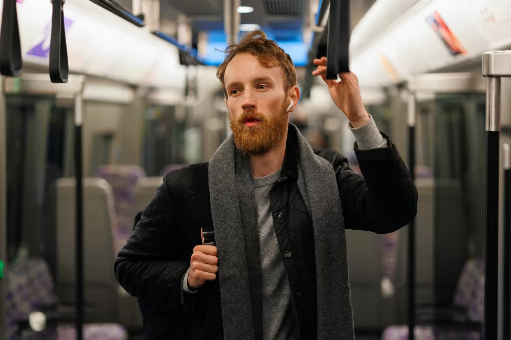 Man in subway train listens to audio book in wireless headphones