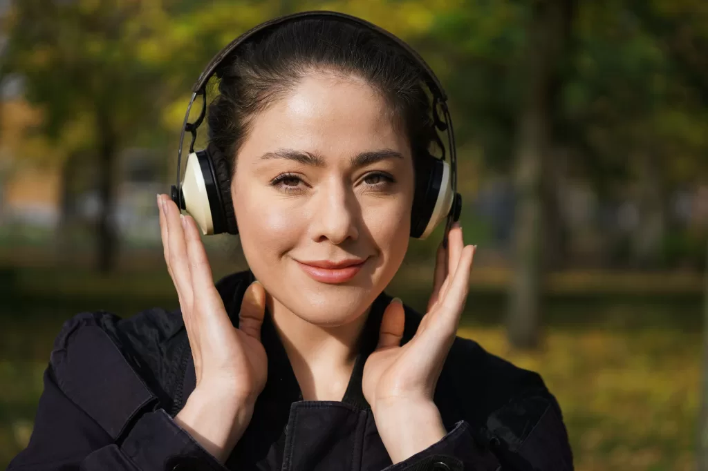 young woman listening to music with cordless headphones outside