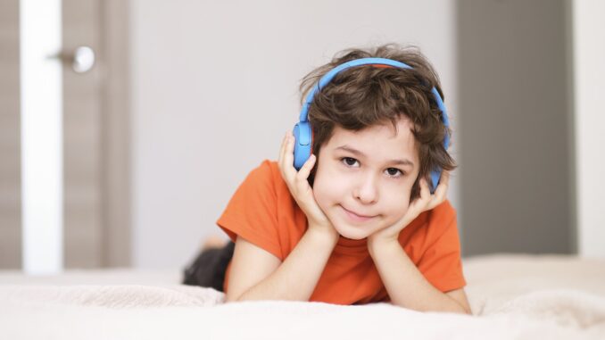 face of a smiling boy listening to music in blue headphones. High quality photo. Photo of little