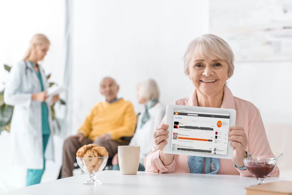 senior woman showing soundcloud stream on digital tablet screen at nursing home