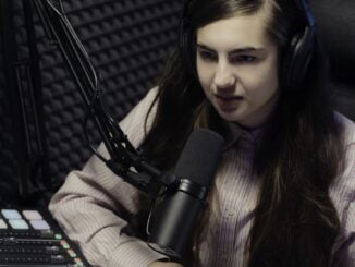 A girl recording a podcast in studio, speaking into a professional microphone, with podcasting equipment visible